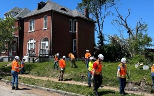 Group of people cleaning up an area in St. Louis following a tornado.