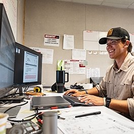 A person smiling while looking at a computer screen