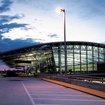 Outdoor image of a terminal thats completely glass and steal with clouds in the sky
