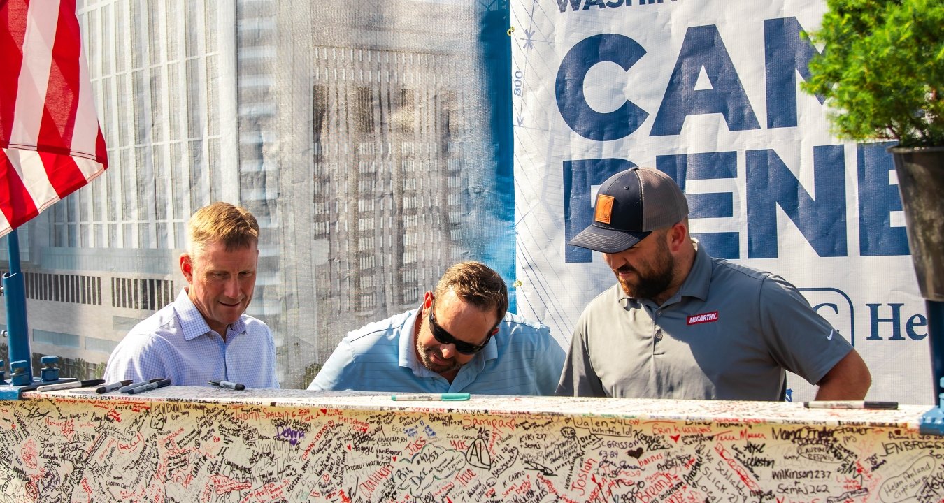 Three people signing a beam.