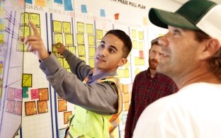 3 people looking at a scrum white board