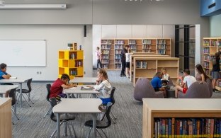 People sitting at tables and chairs in a library