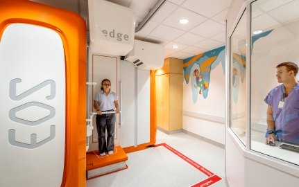 A person standing in the EOS machine while someone else looks on